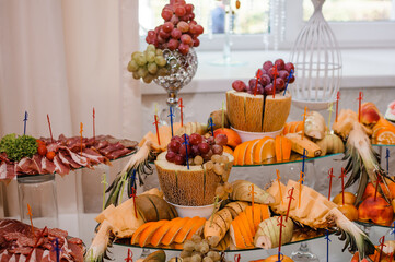Obraz na płótnie Canvas Fruit slicing at a wedding banquet. Watermelon, grapes, strawberry, orange, plum, pear, dinha, peach, kiwi, pineapple, persimmon, apple