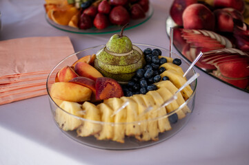 Fruit slicing at a wedding banquet. Watermelon, grapes, strawberry, orange, plum, pear, dinha, peach, kiwi, pineapple, persimmon, apple