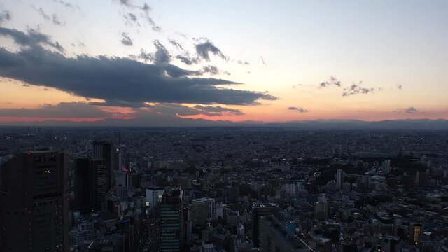 TOKYO, JAPAN : Aerial high angle sunset CITYSCAPE of TOKYO. View of dramatic clouds and buildings around Shibuya. Japanese city life and metropolis concept. Long time lapse tracking shot dusk to night