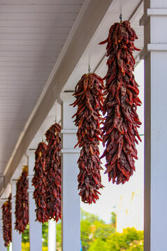 Red chili or chilli pepper ristras hanging outside building in New Mexico, Southwest USA. Santa Fe, United States of America.  String of dried chili pepper pods is called a ristra of chiles