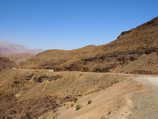Fototapeta na wymiar Winding route through Atlas Mountains, Morocco. Rough gravel route with amazing landscapes. Exciting virage and great viewpoint in mountainous scenery 