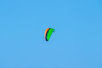 Bright sail for kitesurfing against a cloudless blue sky. Winter sports