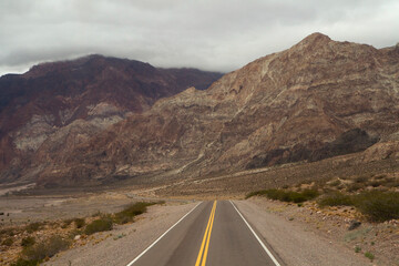 Road trip into the arid desert. Traveling along the asphalt highway across the rocky mountains.