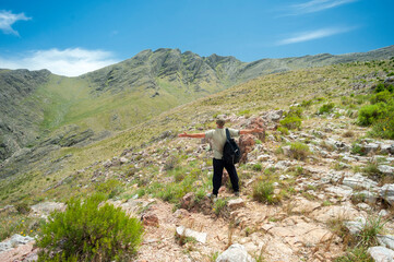 man on the mountain opening his arms outdoors on a sunny day in a vast landscape