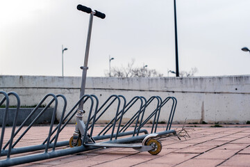 Un patinete no eléctrico estacionado en una estación de aparcamiento para bicicletas. Scooter para niños.