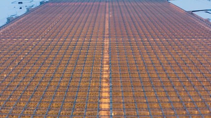 Aerial side view of large industrial greenhouses for growing plants in winter. light pollution. winter day at sunset. Flying along modern plantation glasshouse area. growing plants vegetables flowers