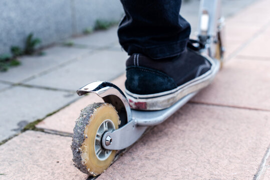 Detalle de la rueda trasera de un patinete el&eacute;ctrico. Rueda gastada, muy usada, vieja y rota llena de peque&ntilde;as piedras.