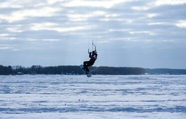 Snowboarders on the parachute ride on the frozen lake