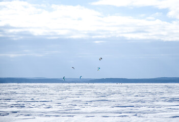 Snowboarders on the parachute ride on the frozen lake