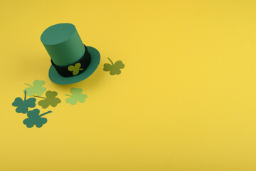 St Patricks Day leprechaun hat and clover leaves on yellow background.