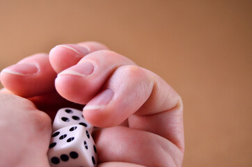 Playing dice white in a close-up fist on a brown background with a copy space. High quality photo