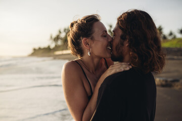 On the beach sand against the ocean, a loving couple gently embraced kissing. High quality photo