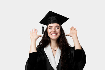 Graduate girl with master degree in black graduation robe and cap on white background. Happy young woman careerist have success in her business.