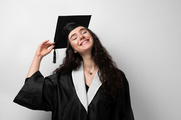 Graduate girl with master degree in black graduation robe and cap on white background. Happy young woman careerist have success in her business.