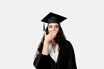 Surprised bachelor girl in graduation robe and cap on white background. Happy and funny young woman smile. Student achieve master degree in univesity