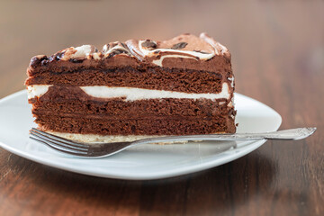 A slice of chocolate cake with cream and decoration.