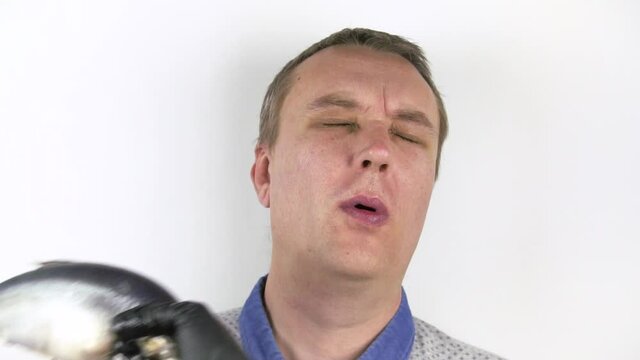 The fishtail hits the man in the face. A portrait of a man who was hit in the face by a fish. He grimaces into the camera. Slow motion. Close-up. White background.
