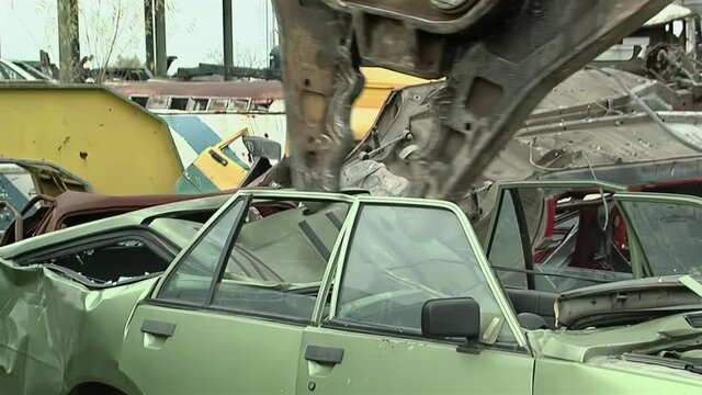Sinking Teeth into Scrap Metal, Giant Hydraulic Pincers of a Junkyard Crane Dismantling an Old Car at Scrap Yard.