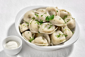 Boiled or steamed pelmeni in white bowl. Pelmeni are homemade pasta with mince meet filling wrapped...