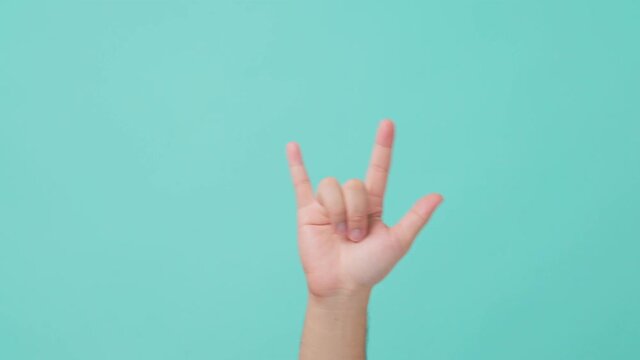Close-up shot of human hand raising, with ILY sign language gesture.