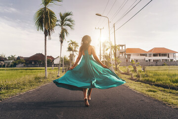 On the way to the side of villas in Bali runs barefoot girl in a long flying dress. High quality photo - Powered by Adobe