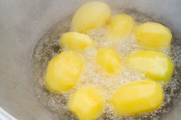 Golden potatoes are fried in boiling oil in a cauldron