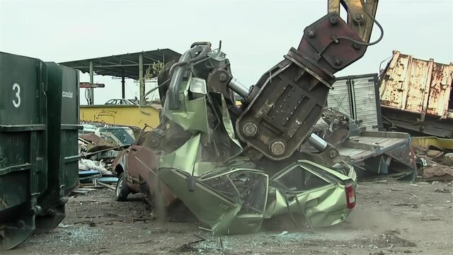 Giant Claw of Junkyard Crane crushing Old Car.  