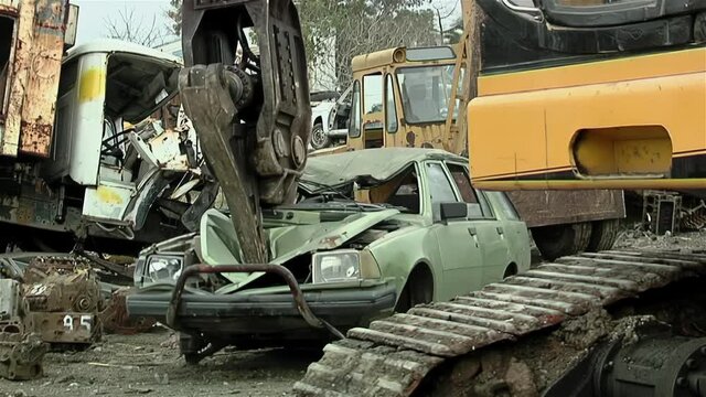 Sinking Teeth into Scrap Metal, Giant Hydraulic Pincers of a Junkyard Crane lifting an Old Car at Scrap Yard.