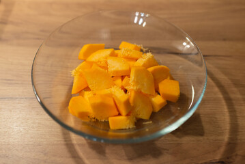 A glass bowl with diced pumpkin isolated on wooden background