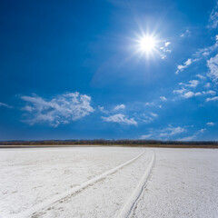 dry saline land with car track under a sparkle sun