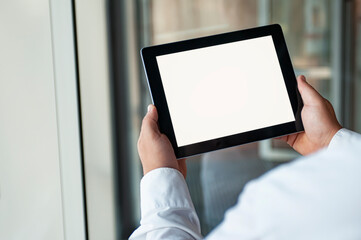 Mockup image of a Man holding black tablet in hand with blank white screen on background in the door.
