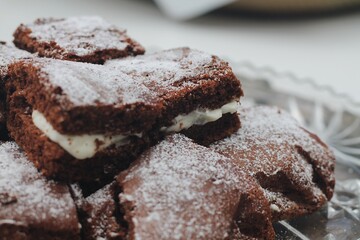Close up  Macro photography of stacked chocolate brownie cake with cream white frosting and powdered sugar