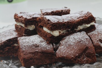 Close up photography of  stacked chocolate brownie cake with cream white frosting and powdered sugar