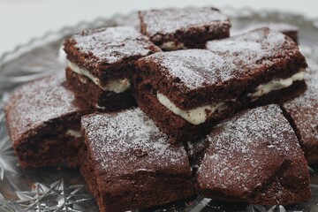 Close up photography of chocolate brownie cake with cream white frosting and powdered sugar