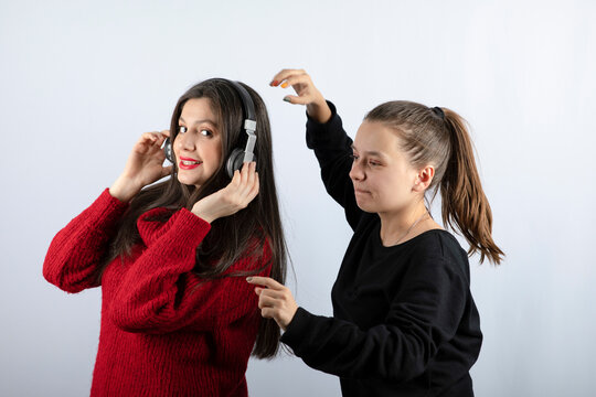 Young girl model with ponytail taking headphones from brunette woman