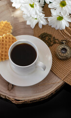 White cup with black coffee. Morning coffee, breakfast, cookies, tropical leaf, wicker hat. Summer sunny background. Breakfast on vacation at the hotel. Traveling at sea, close-up.