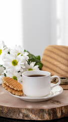 Fototapeta na wymiar White cup with black coffee. Morning coffee, breakfast, cookies, tropical leaf, wicker hat. Summer sunny background. Breakfast on vacation at the hotel. Traveling at sea, close-up.