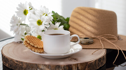 White cup with black coffee. Morning coffee, breakfast, cookies, tropical leaf, wicker hat. Summer sunny background. Breakfast on vacation at the hotel. Traveling at sea, close-up.