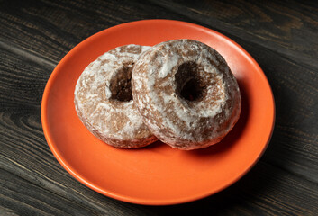 Two homemade round gingerbread cookies with icing in a orange plate. Idea for a delicious breakfast or dinner.