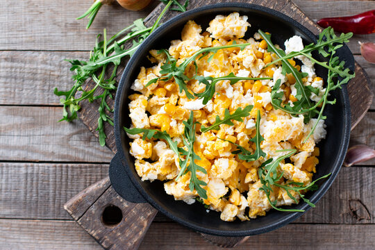Fresh scrambled eggs with corn, cheese, herbs and vegetable on a table, top view. Delicious homemade breakfast