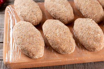 Frozen cutlets lie on a wooden board. Raw meat semi-finished products