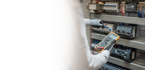 Electricians hands testing current electric in control panel