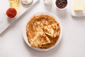 Russian traditional breakfast for Shrovetide of thin pancakes served different fillings sour cream, red caviar, honey, chocolate on white. Top view.