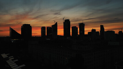 Silhouettes of the buildings in Warsaw on the red sky after sunset. Illuminated skyscrapers in the city. High quality photo