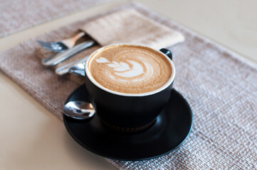 Cup of art latte on a cappuccino coffee on beige background