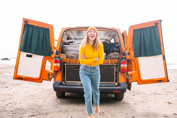 Woman on vacation with her orange van on the beach