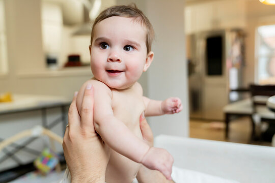 Happy chubby baby in diaper in dad's hands
