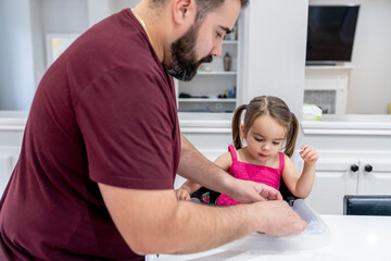 Obraz premium Dad giving toddler daughter food in kitchen 