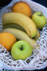 Crochet bag filled with bananas, apples and lemons. Selective focus.