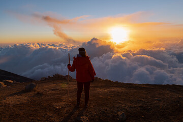 Fototapeta premium Young climber on top of the Acatenango volcano in Guatemala watching the sunset - woman hiking enjoying the sunset